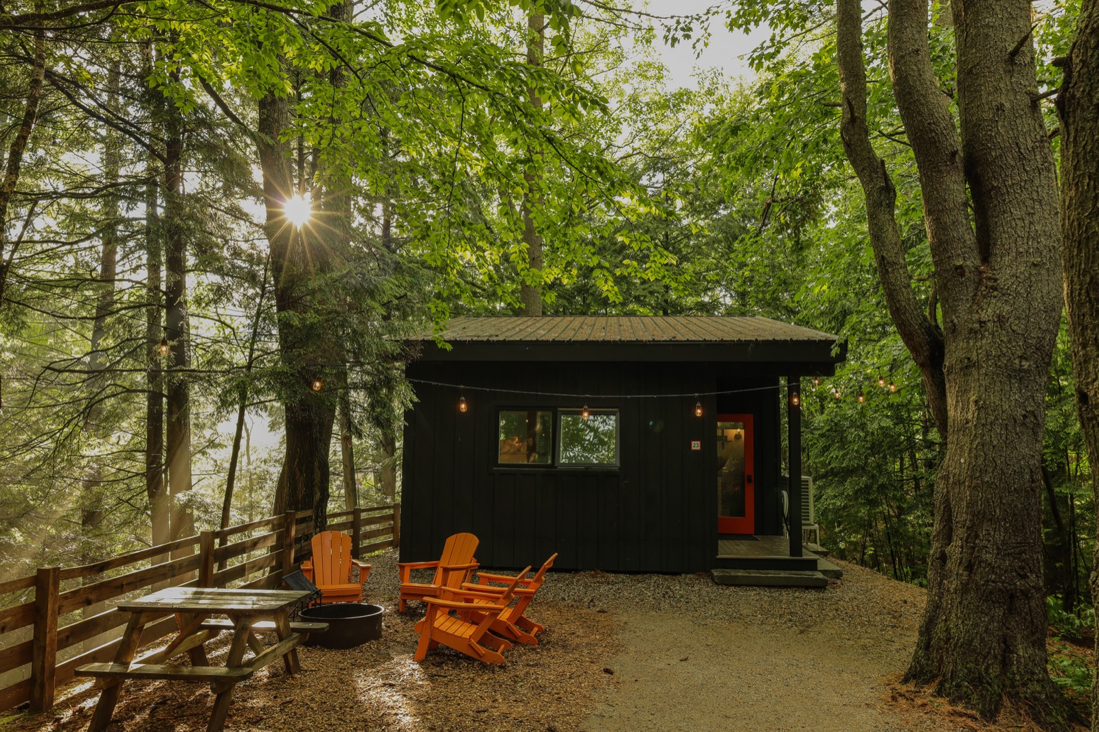 A Haven cabin at sunset with Adirondack chairs around the fire pit