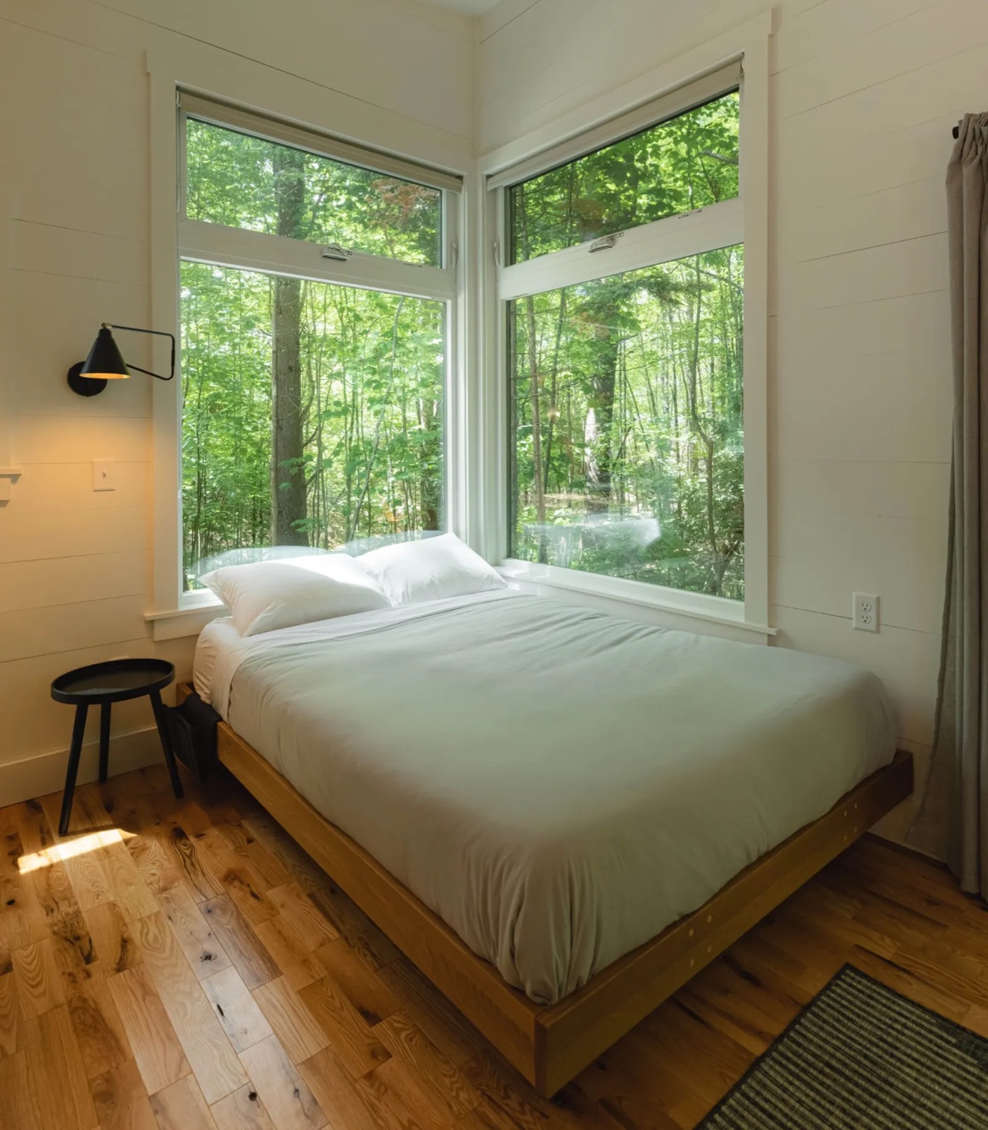 Inside a Haven cabin: a queen bed, a kitchenette and large windows onto the woods